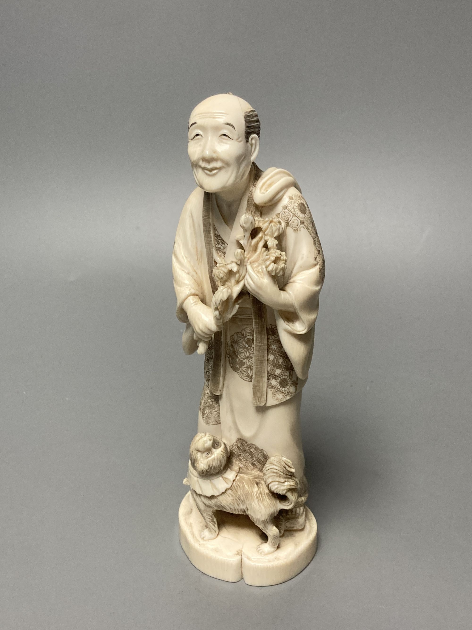 A Japanese ivory okimono of a man and dog, signed tablet to base, early 20th century, 19cm